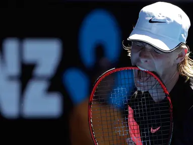 Petenis Kanada Denis Shapovalov menggigit raketnya dengan frustrasi saat pertandingan putaran kedua melawan petenis Prancis Jo-Wilfried Tsonga di kejuaraan tenis Australia Terbuka di Melbourne, Australia, (17/1). (AP Photo / Dita Alangkara)