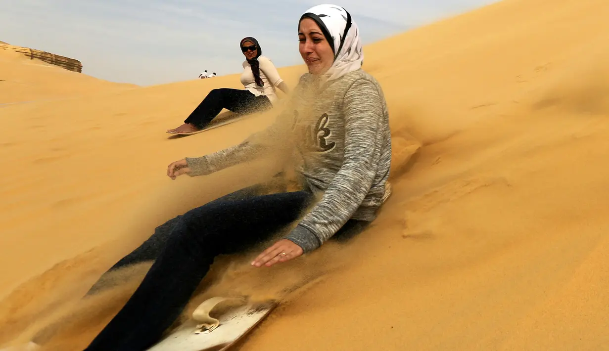 Seorang wanita mencoba berseluncur menggunakan papan sandboards di gurun pasir Wadi el-Rayan Fayoum, Mesir (18/11). Di gurun ini menyajikan banyak hiburan dan pariwisata salah satunya, berseluncur di pasir atau sandboarding. (Reuters/Mohamed Abd El Ghany)