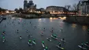 Para peserta Nautic Paddle Race atau lomba dayung sambil berdiri melintas dekat Katedral Notre-Dame di Paris, Minggu (8/12/2019). Sekitar 1000 pesaing ikut serta dalam lomba sejauh 11 kilometer menyeberangi sungai Seine dengan pemandangan kota Paris. (Photo by Olivier MORIN / AFP)