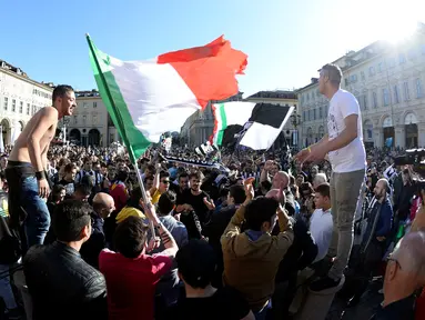 Suporter Juventus mengibarkan bendera Itali merayakan kemenangan usai merebut gelar Serie A Italia di pusat kota Turin, Italia (25/4). Juventus sukses meraih lima gelar juara Serie A dalam lima musim beruntun. (REUTERS/Giorgio Perottino) 