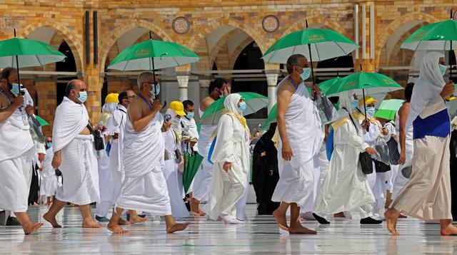 Jemaah yang memegang payung untuk melindungi diri dari panas tiba di Masjidil Haram pada awal musim haji, Arab Saudi, Sabtu (17/7/2021). Pemerintah Arab Saudi mengklaim ibadah haji tahun lalu hanya diikuti 1.000 orang, sementara media lokal menyebut ada 10 ribu orang. (FAYEZ NURELDINE/AFP)