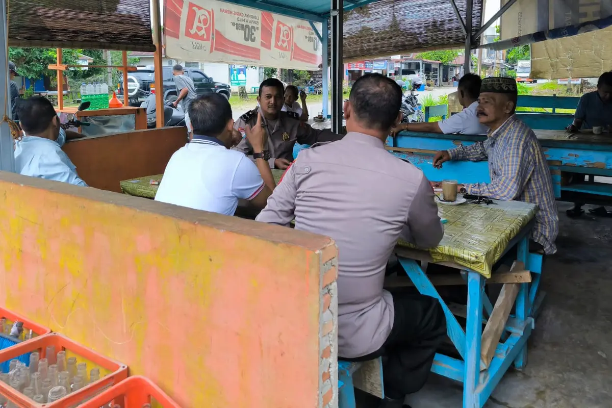 Personel Polres Rokan Hulu berdialog dengan warga di warung kopi.