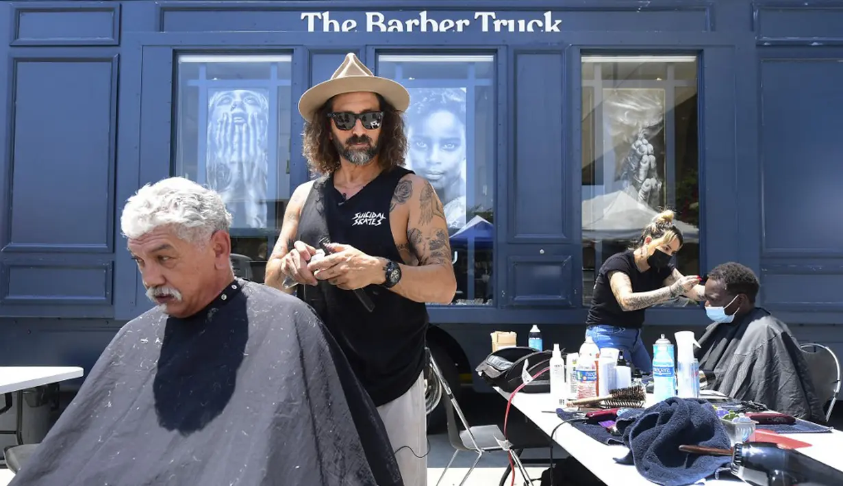 Penata rambut selebriti Jason Schneidman dari The Men's Groomer mencukur rambut Samuel Velasquez saat cukur rambut gratis untuk para tunawisma dalam Los Angeles Mission di Los Angeles, California, Amerika Serikat, 12 Juli 2021. (Frederic J. BROWN/AFP)