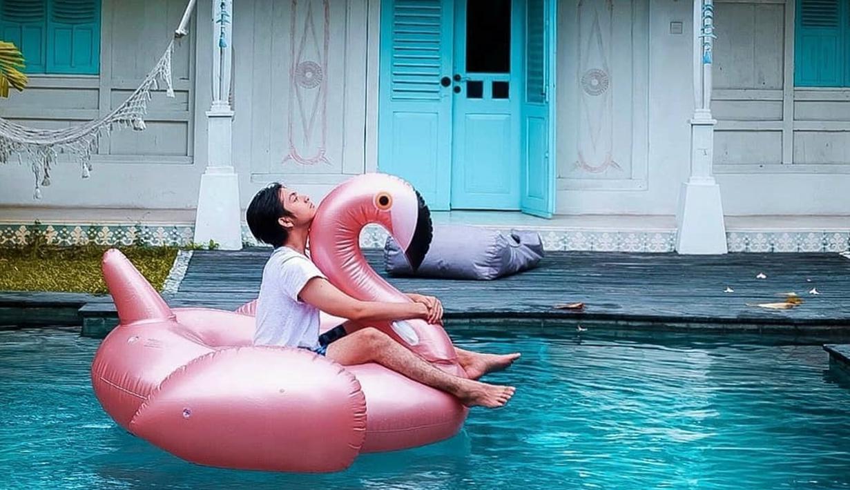 Duduk santai di atas giant float falminggo sembari nikmatin suasana, begini cara pemain film 'Sunyi' menghabiskan waktu di Lombok. Hanya dengan tshirt putih polos dan pants, gaya liburan Angga terlihat simple dan tetap memesona.(Liputan6.com/IG/@anggayunandareal16)