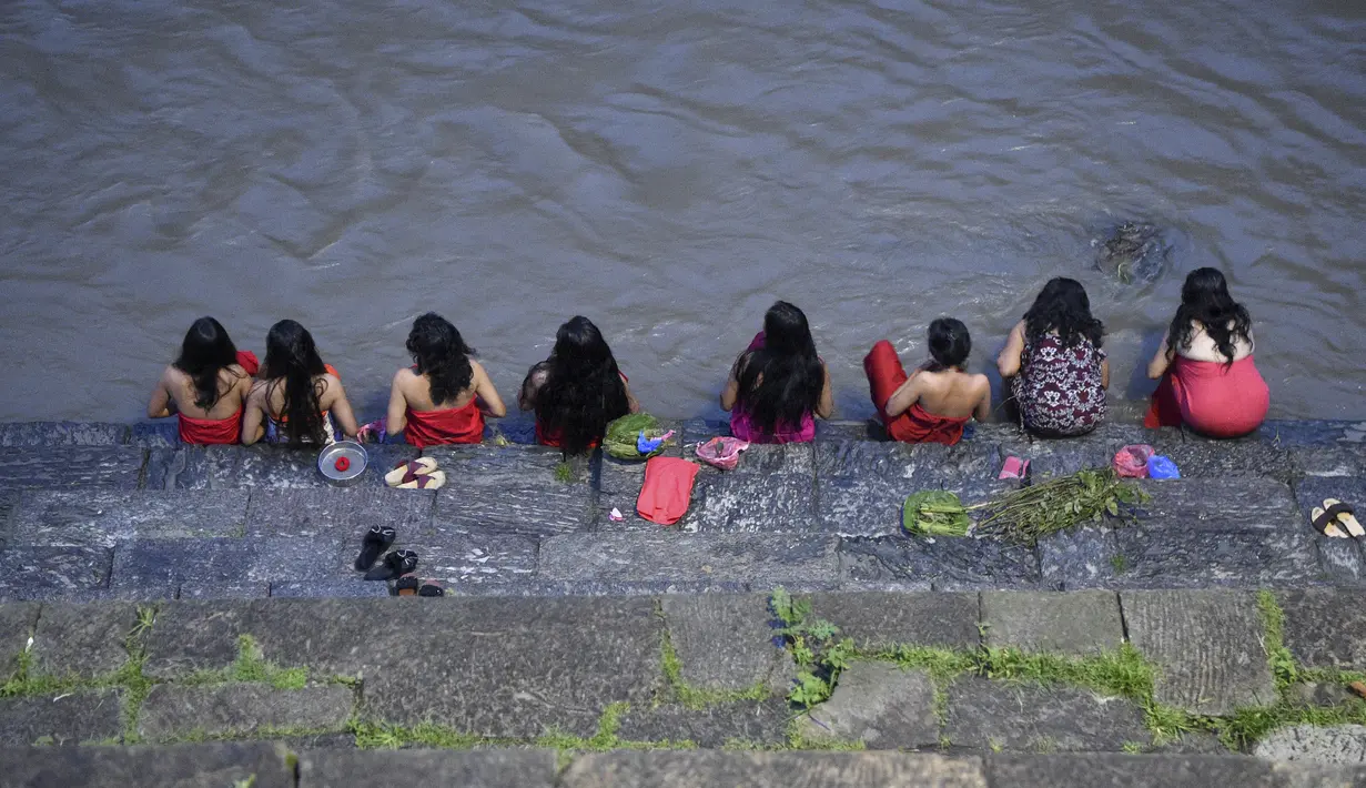 Sejumlah wanita Hindu Nepal mandi suci di sungai Bagmati selama festival Rishi Panchami di Kathmandu (3/9/2019). Di festival ini para wanita berpuasa di siang hari dan berdoa untuk umur panjang untuk suami mereka. (AFP Photo/Prakash Mathema)