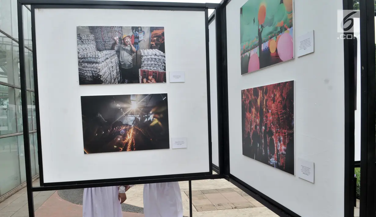 Siswa SD Negeri Menteng 01 mengamati karya foto yang dipamerkan dalam pameran fotografi Rekam Jakarta di Taman Menteng, Kamis (29/8/2019). Kegiatan tersebut dalam rangka edukasi bagi siswa mengenal profesi foto jurnalistik. (merdeka.com/Iqbal S Nugroho)