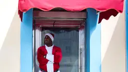 Seorang pria mengenakan pakaian Santa Claus menunggu pelanggan di pintu masuk sebuah kafe di Havana, Kuba (28/12). Havana merupakan kota terbesar dan pelabuhan utama di Kepulauan Hindia Barat. (AP Photo / Desmond Boylan)