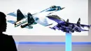 Salah satu pengunjung memerhatikan replika pesawat jet tempur buatan Rusia, Sukhoi SU-35, di pameran dirgantara Farnborough di Hampshire, Inggris, (14/7/2014). (AFP PHOTO/Leon Neal)