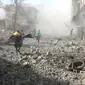 Penyelamat berlari untuk membantu korban serangan udara pasukan pemerintah di Ghouta Timur, Damaskus, Suriah, Selasa (20/2). Kelompok pemantau dan paramedis Suriah mengatakan serangan itu menewaskan 98 orang. (Syrian Civil Defense White Helmets via AP)