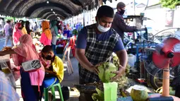 Seorang pria yang mengenakan masker menyiapkan minuman kelapa di pasar menjelang berbuka puasa selama bulan suci Ramadan di Provinsi Narathiwat, Thailand, Selasa (5/5/2020). Ramadan kali ini berlangsung di tengah bayang-bayang virus corona COVID-19. (Madaree TOHLALA/AFP)