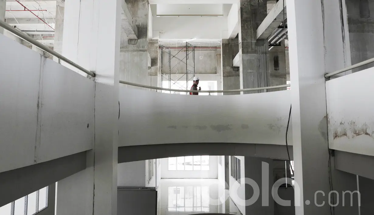 Seorang pekerja melintas di dalam pembangunan wisma Atlet di Kemayoran. Wisma Atlet Kemayoran ini menempati area seluas 10 hektar. (Bola.com/M Iqbal Ichsan)