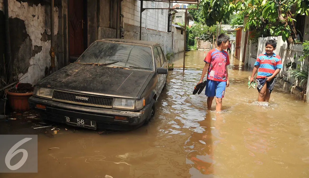 Sejumlah anak melintasi genangan banjir di kawasan komplek Polri jalan Pondok Karya, Mampang, jakarta, kamis (21/4). Akibat pintu air di Depok dibuka kali mampang meluap dan menyebabkan banjir di kawasan tersebut. (Liputan6.com/Gempur M Surya)