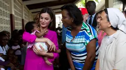 Ratu Spanyol Letizia menggendong seorang bayi perempuan dalam kunjungannya ke rumah sakit di daerah kumuh Soleil, Haiti, 23 Mei 2018. Ini merupakan kunjungan pertama Ratu Letizia ke negara termiskin di benua Amerika tersebut. (AP/Dieu Nalio Chery)