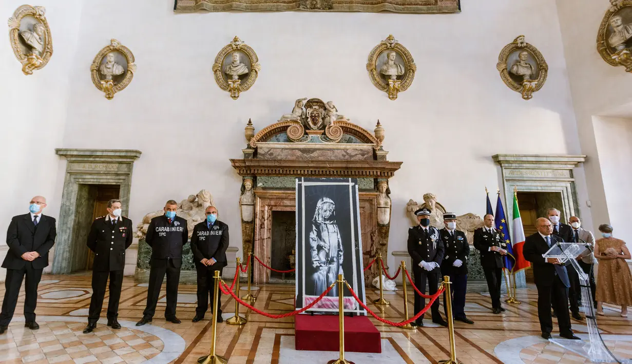 Lukisan seniman Inggris Banksy yang menggambarkan sosok perempuan muda dengan ekspresi sedih dikembalikan ke Duta Besar Prancis untuk Italia, Christian Masset (keempat kanan) setelah dicuri selama upacara di Kedutaan Besar Prancis di Roma (14/7/2020). (AP/Photo/Domenico Stinellis)