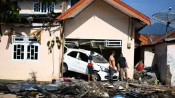 Warga membersihakn rumah mereka setelah gempa bumi dan tsunami menghantam kota Palu, Sulawesi Tengah, Kamis (4/10). BNPB menyebut, hingga Kamis sore, jumlah korban meninggal akibat gempa dan tsunami Palu mencapai 1.558 orang. (AFP/Jewel SAMAD)