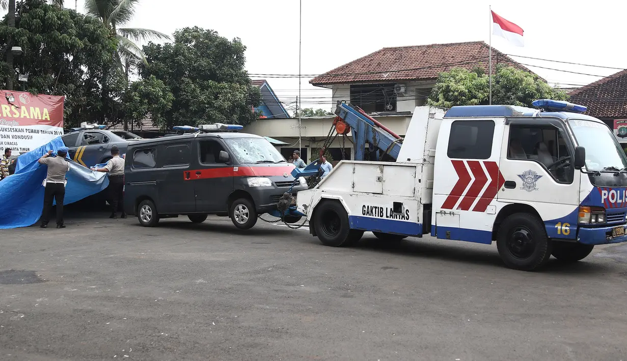 Petugas Ditlantas Polda Metro Jaya membawa mobil dinas polisi di Mapolsek Ciracas, Jakarta, Rabu (12/12). Selain mobil, bangunan Polsek Ciracas juga ikut dirusak massa. (Liputan6.com/Herman Zakharia)