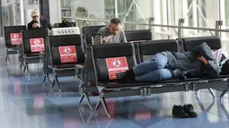 Orang-orang beristirahat di lobi Bandara Internasional Haneda yang sepi di Tokyo, Senin (28/12/2020). Saat ini Jepang sudah mencatat delapan kasus terkait varian baru covid-19 yang pertama kali terdeteksi di Inggris.  (AP Photo/Koji Sasahara)