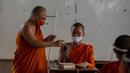 Biksu senior menyemprot mikrofon dengan disinfektan saat biksu muda belajar agama di Molilokayaram Educational Institute, Bangkok, Thailand, Rabu (15/4/2020). Sekitar 200 biksu muda tetap bersekolah kendati Thailand menutup semua sekolah selama lockdown akibat COVID-19. (AP Photo/Gemunu Amarasinghe)