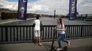 Seorang wanita menggunakan skuter melintasi jembatan saat anak lelaki melihat sungai Moskva jelang inal Piala Dunia 2018 antara Prancis melawan Kroasia di Moskow, Rusia, (13/7). (AP Photo / Thanassis Stavrakis)