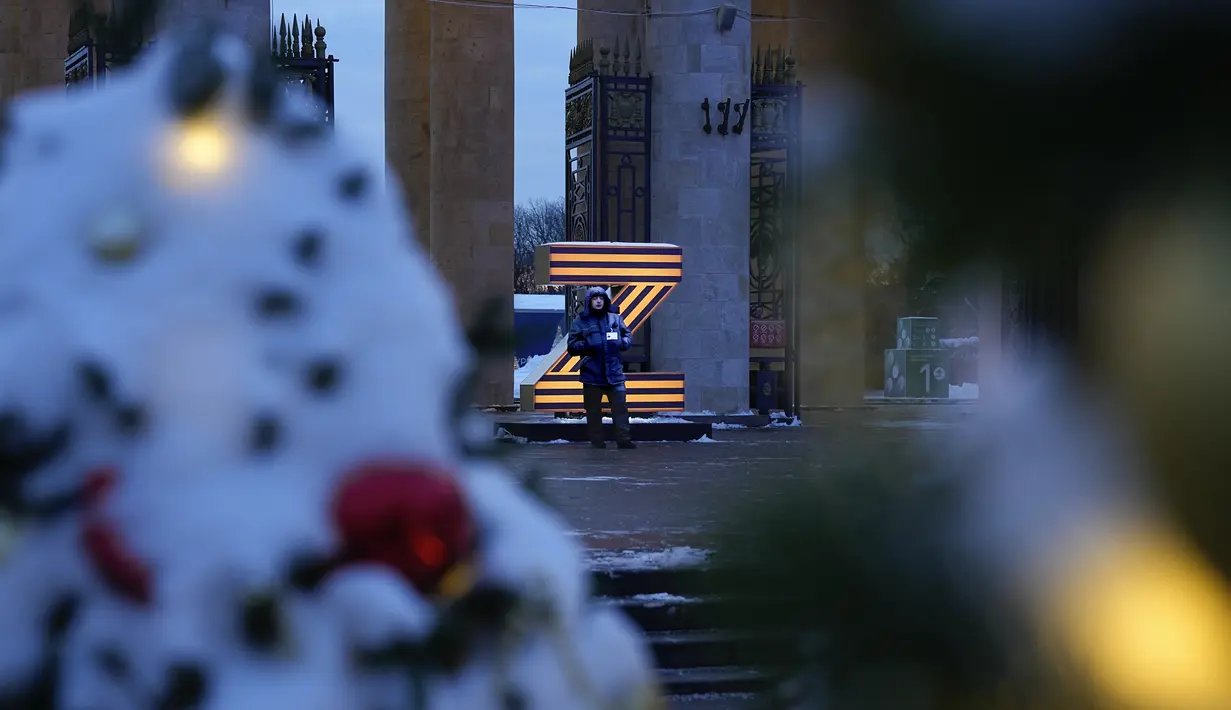 Seorang petugas keamanan berdiri di pintu masuk Taman Gorky yang dihias untuk perayaan Natal dan Tahun Baru di Moskow, Rusia, Selasa (20/12/2022). Perintah Invasi Ukraina merupakan perintah dari presiden Rusia Vladimir Putin. (AP Photo/Alexander Zemlianichenko)