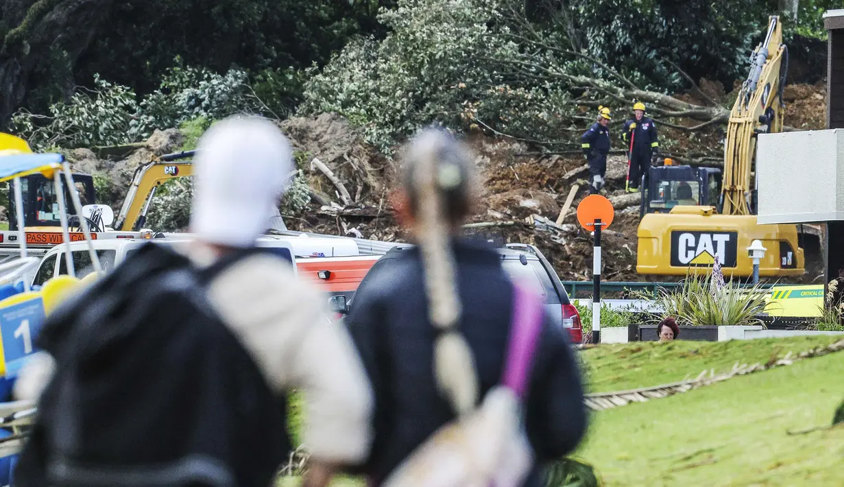 Operasi pencarian dan penyelamatan masih berlangsung di lokasi perkemahan Gunung Maunganui yang merupakan salah satu destinasi populer di pantai utara Selandia Baru. Tampak dalam foto, sepasang suami istri melihat tanah longsor sementara pencarian sedang dilakukan oleh layanan darurat setempat untuk orang hilang di Gunung Maunganui, Tauranga, Selandia Baru pada Kamis 22 Januari 2026. (DJ MILLS/AFP)