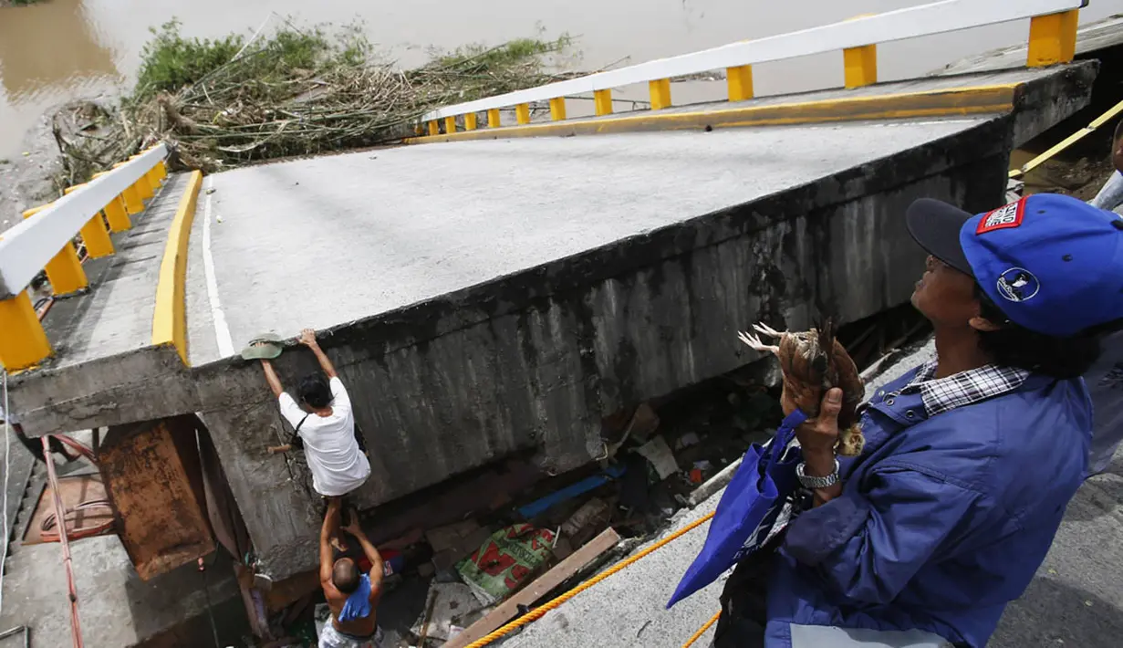 Topan Rammasun, merupakan badai terkuat yang melanda Filipina, dikabarkan beberapa ruas jalan di Luzon, rusak. Tampak warga warga memanjat di sebuah jembatan hancur akibat terpaan topan Rammasun, di Batangas, Manila, (17/7/2014). (REUTERS/Erik De Castro)