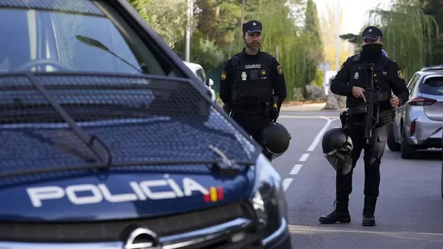 Polisi berjaga-jaga ketika petugas lain dengan rompi kuning berjalan kembali di area yang ditutup di sebelah kedutaan Ukraina di Madrid, Spanyol, Rabu, 30 November 2022. (Paul White/AP)