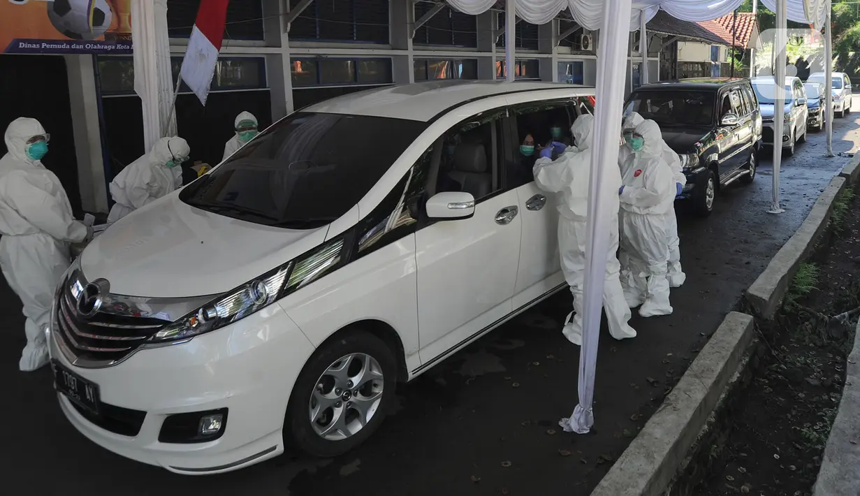 Petugas Dinkes Kota Bogor mengenakan pakaian APD melakukan rapid test Covid-19 dengan sistem drive thru di pelataran Stadion GOR Pajajaran, Bogor, Selasa (31/03/2020). Penyelenggaraan drive thru yang kedua kalinya ini dilakukan kepada lebih dari dua ratus ODP Covid-19. (merdeka.com/Arie Basuki)