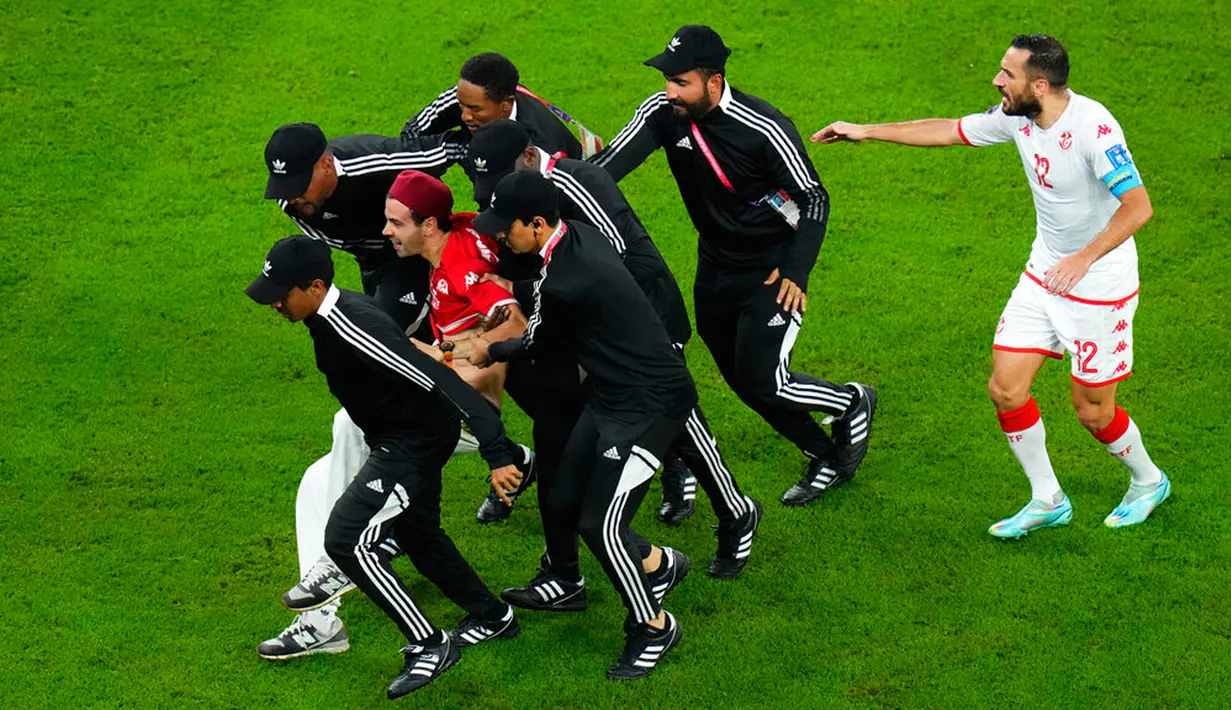 Petugas keamanan membawa penyusup lapangan pada pertandingan sepak bola Grup D Piala Dunia 2022 antara Tunisia dan Prancis di Education City Stadium, Al Rayyan, Qatar, 30 November 2022. Dalam keterangan unggahannya di Instagram, Mino Bei menulis "Tunisia your time is NOW / Remember (Tunisia, waktumu adalah Sekarang / Ingat)." (AP Photo/Petr David Josek)