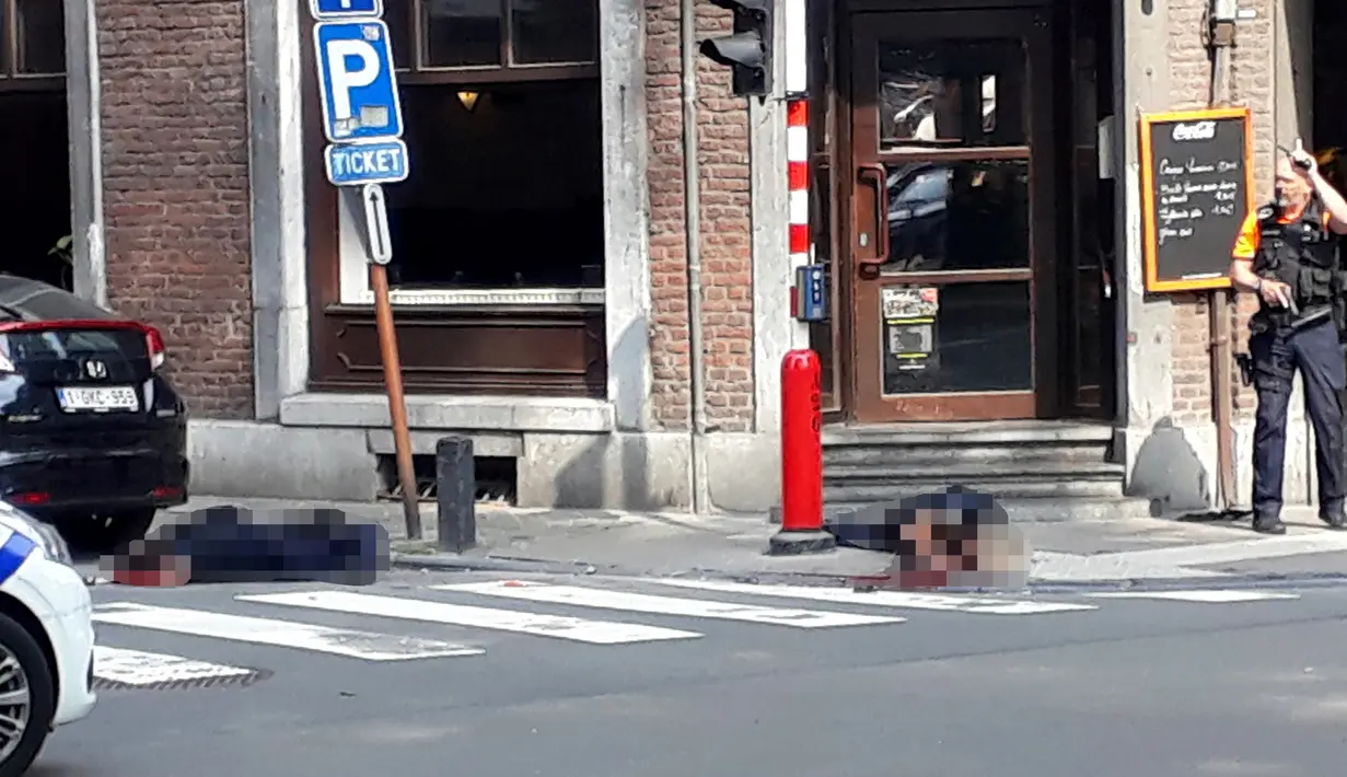 Seorang petugas polisi berdiri di lokasi dekat dua jenazah polisi korban penembakan di Liege, Belgia (29/5). Seorang pria menembak mati tiga orang di dekat sebuah kafe di Kota Liege, Belgia, Selasa waktu setempat. Dua di antara korban adalah polisi. (AP)
