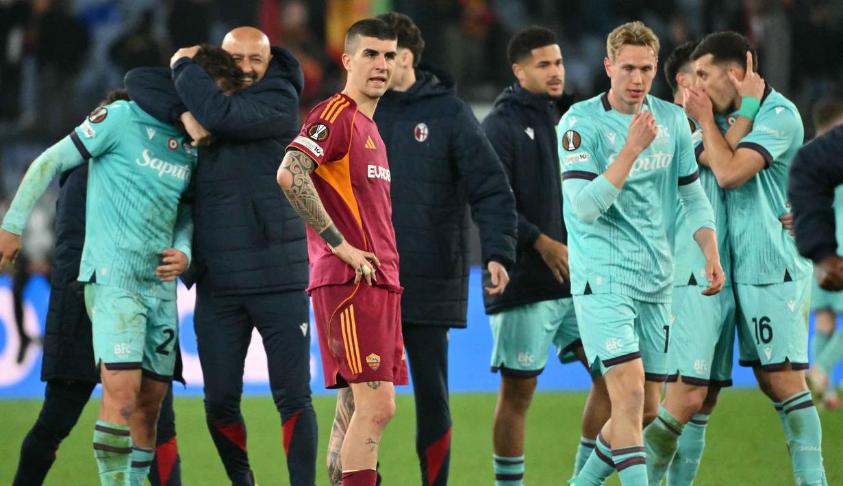 Duel harus memanjang ke fase extra time setelah kedua tim berbagi skor 3-3 pada waktu normal. Tampak dalam foto, ekspresi bek AS Roma, Gianluca Mancini (tengah) saat para pemain Bologna merayakan kemenangan setelah pertandingan leg kedua 16 besar Liga Europa 2025/2026 di Stadion Olimpico, Kamis (19/3/2026) waktu setempat atau Jumat 20 Maret 2026 dini hari WIB. (Alberto PIZZOLI/AFP)