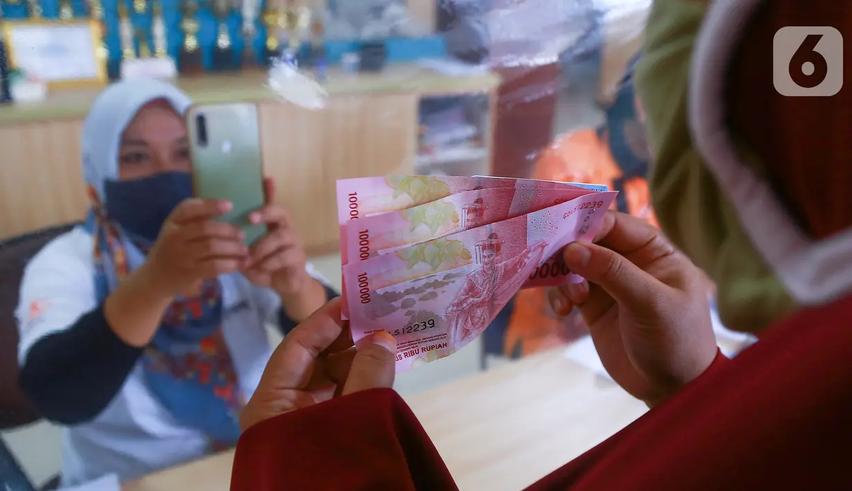 Warga menunjukkan Bantuan Sosial Tunai (BST) senilai Rp300 ribu kepada petugas di Kelurahan Pondok Benda, Kecamatan Pamulang, Tangerang Selatan, Minggu (10/01/2021). BST senilai Rp300 ribu akan disalurkan selama empat bulan berturut-turut mulai dari Januari - April 2021. (Liputan6.com/Fery Pradolo)