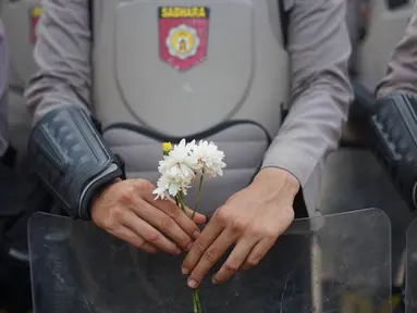 Personel polisi memegang bunga saat mengamankan aksi unjuk rasa Badan Eksekutif Mahasiswa Seluruh Indonesia (BEM SI) di sekitar DPR RI, Jakarta, Selasa (1/10/2019). Selain berorasi secara damai, mahasiswa membagikan bunga untuk para polisi yang mengawal aksi mereka. (Liputan6.com/Immanuel Antonius)