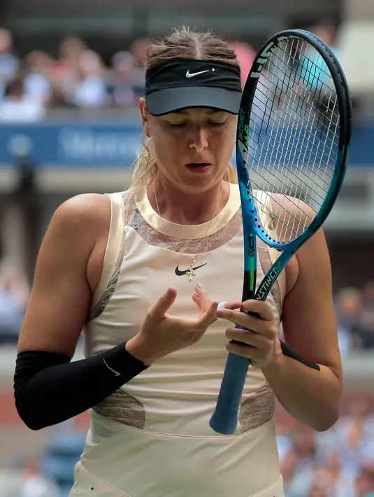 Maria Sharapova memeriksa pembungkus jari kanannya cedera saat berhadapan dengan Anastasija Sevastova dari Latvia di babak keempat grand slam AS Terbuka 2017 di New York (3/9). Sevastova menang 5-7, 6-4, 6-2 atas Sharapova. (AP Photo/Andres Kudacki)