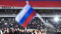 Seorang peserta mengibarkan bendera Rusia saat mendegarkan pidato Vladimir Putin dalam sebuah kampanye di stadion Luzhniki di Moskow (3/3). Putin pun telah bersiap untuk memperoleh periode keempatnya sebagai presiden Rusia. (AFP/Kirill Kudryavtsev)