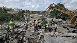 Para pekerja pertahanan sipil Lebanon menyisir reruntuhan, sehari setelah serangan Israel di desa Deir Qanun al-Nahr, Lebanon Selatan, pada Rabu 20 Mei 2026. (KAWNAT HAJU/AFP)