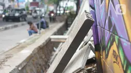 Kondisi tembok Jalan Juanda yang ambruk di kawasan Depok, Jawa Barat, Senin (2/12/2019). Kondisi tembok yang dipenuhi mural tersebut mulai rapuh dan sebagian sisinya telah ambruk serta miring sehingga membahayakan pejalan kaki. (Liputan6.com/Immanuel Antonius)