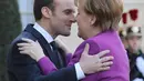 Presiden Prancis Emmanuel Macron (kiri) berpelukan dengan Kanselir Jerman Angela Merkel saat menyambut kedatangannya di Istana Presiden Eylsee di Paris (16/3). (AFP Photo/Ludovic Marin)
