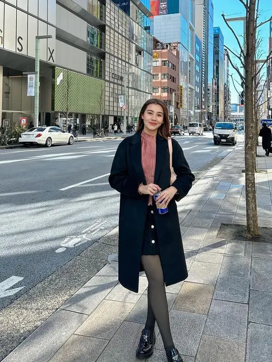 Aaliyah mengenakan coat hitam dipadukan inner pink dan mini skirt hitam serasi dengan stocking dan sepatu loafers dari Prada seharga Rp20 jutaan.   [@aaliyah.massaid]