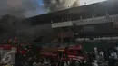 Petugas pemadam kebakaran berusaha memadamkan api sementara sejumlah pedagang terlihat sibuk menyelamatkan barang dagangan mereka yang masih ada di dalam Pasar Senen, Jakarta Pusat, Kamis (19/1). (Liputan6.com/Faizal Fanani)