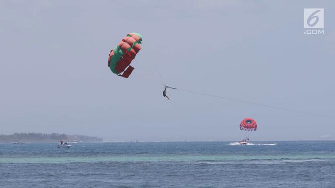Wisatawan mengikuti permainan Parasailing di pantai Nusa Dua Bali, Rabu (10/10). Kementerian Pariwisata menyiapkan 63 paket wisata untuk turis yang berkunjung selama pertemuan IMF - Bank Dunia Bali 2018. (Liputan6.com/Angga Yuniar)