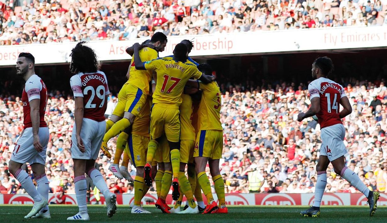 Selebrasi gol yang ditumpahan pemain Crystal Palace pada laga lanjutan Premier League yang berlangsung di Stadion Emirates, Minggu (21/4). Arsenal kalah 2-3 kontra Crystal Palace. (AFP/Adrian Dennis)
