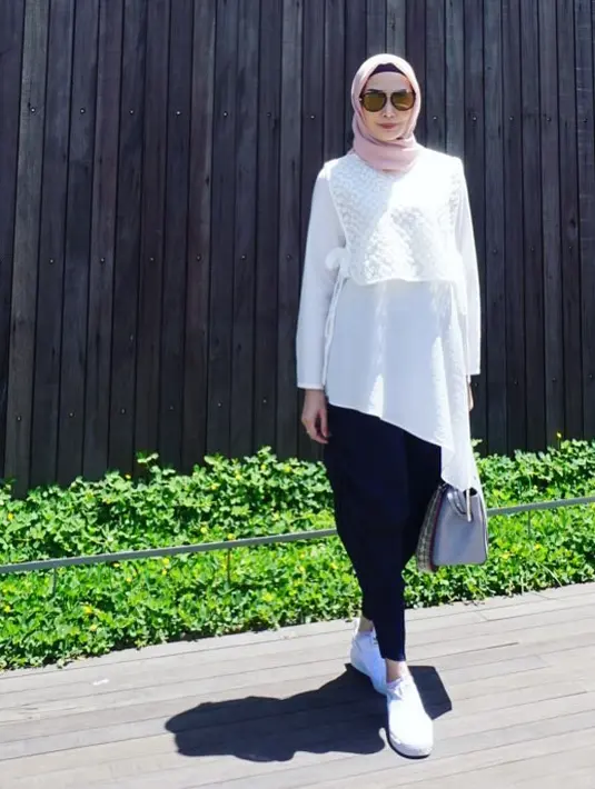 Paduan celana hitam dengan blus putih potongan asimetrik ini membuat Fenita sangat modis. Terlebih dengan sneakers dan kacamata gayanya. Berhijab, bukan lah halangan baginya untuk tetap stylish. (Instagram/fenitarie)
