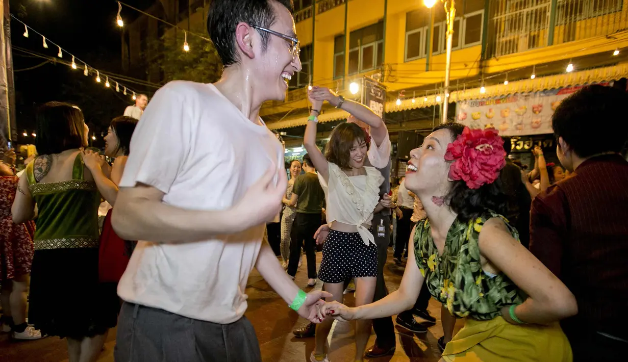 Pria dan wanita menari di depan kuil Phra Pathom Chedi di provinsi Nakhon Pathom, Thailand (25/2). Lebih dari 300 peserta termasuk penari asing bernari menghebohkan sebuah jalan sekitar satu jam. (AFP Photo/Thai News Pix/Krit Promsakla Na Sakolnakorn)