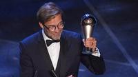 Pelatih Liverpool, Jurgen Klopp mengangkat trofi Pelatih Terbaik Dunia 2019 versi FIFA saat memberi sambutan di teater La Scala Milan, Italia utara (23/9/2019). Klopp menyabet mengalahkan Pep Guardiola dan Mauricio Pochettino. (AFP Photo/Marco Bertorello)