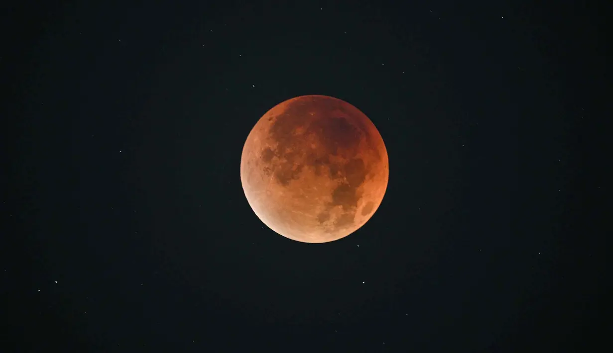 Momen ini sangat ditunggu para pencinta astronomi dan penikmat langit malam. Tampak dalam foto, “Blood Moon” terlihat selama gerhana bulan di langit malam di Shanghai, China pada 8 September 2025. (Hector RETAMAL/AFP)