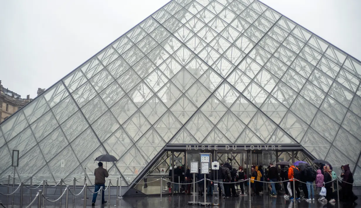 Turis berdiri di luar museum Louvre di Paris, Prancis pada Minggu (1/3/2020). Louvre, museum yang paling banyak dikunjungi di dunia, ditutup sementara untuk pengunjung setelah para staf menolak bekerja di tengah kekhawatiran terjangkit virus corona tipe baru, Covid-19. (AP/Rafael Yaghobzadeh)
