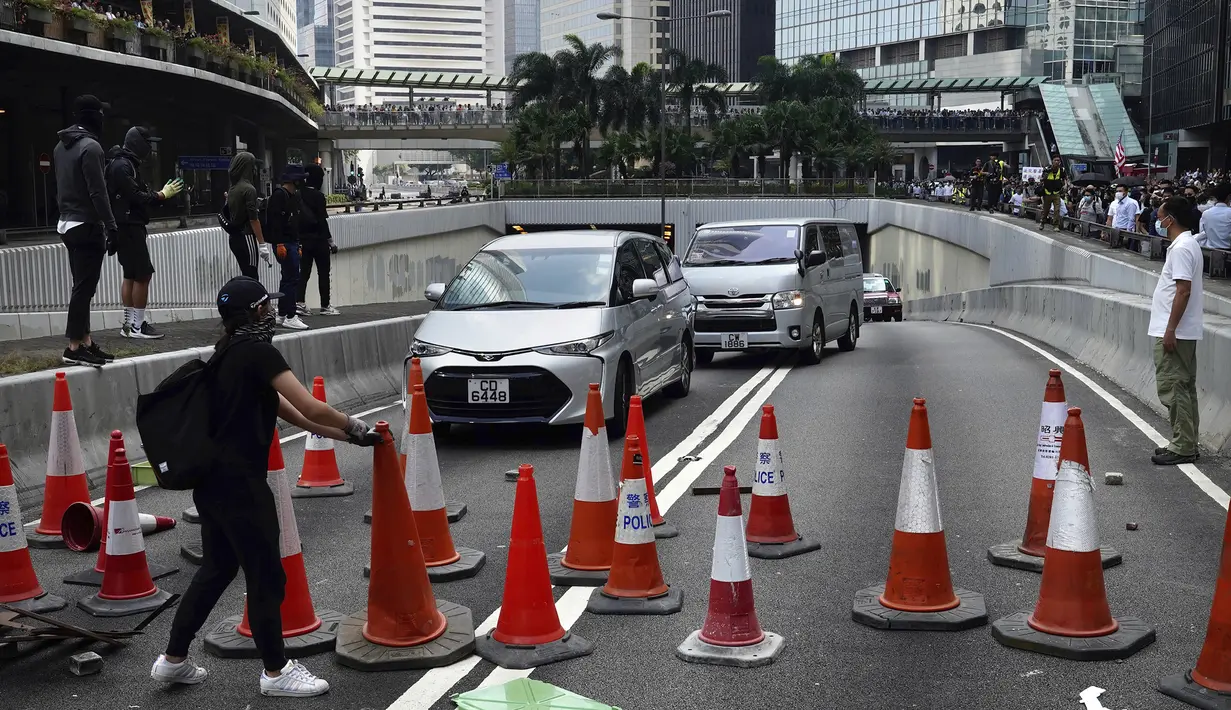 Demonstran menempatkan kerucut lalu lintas untuk menghalangi jalan selama protes di distrik keuangan di Hong Kong (14/11/2019). Warga Hong Kong mengalami hari keempat kemacetan lalu lintas dan gangguan angkutan massal ketika pengunjuk rasa menutup beberapa jalan utama. (AP Photo/Vincent Yu)