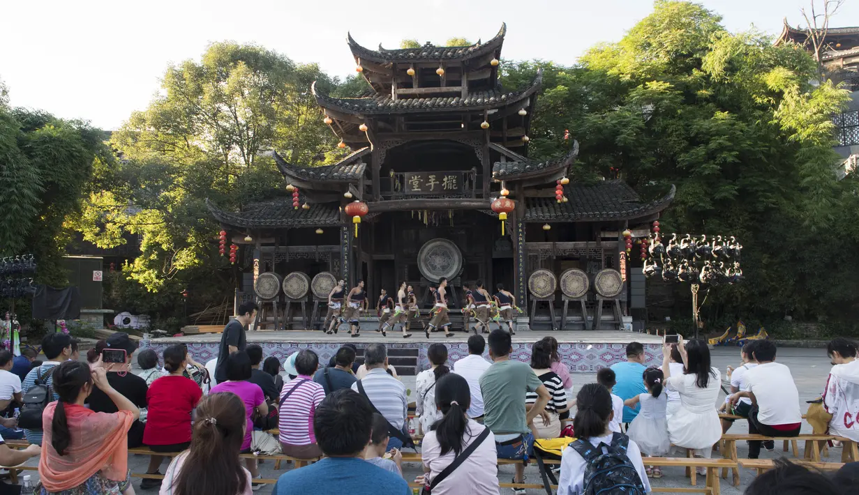 Para wisatawan menyaksikan pertunjukan di objek wisata Kota Furong di Wilayah Yongshun, Provinsi Hunan, China tengah (2/8/2020). Dengan menerapkan sejumlah langkah pencegahan epidemi, objek wisata tersebut mencatat peningkatan kunjungan turis selama liburan musim panas. (Xinhua/Chen Sihan)