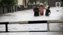 Warga berjalan menyusuri banjir yang menggenangi kawasan Jalan Wolter Monginsidi Jakarta dan sekitarnya, Sabtu (20/2/2021). Hujan yang mengguyur Jakarta sejak Jumat (19/2) membuat sejumlah titik di Jakarta terendam banjir. (Liputan6.com/Helmi Fithriansyah)